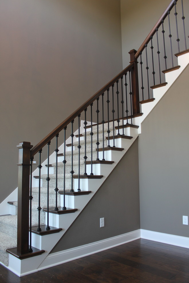 This is an example of a large country wood curved staircase in Other with painted wood risers.