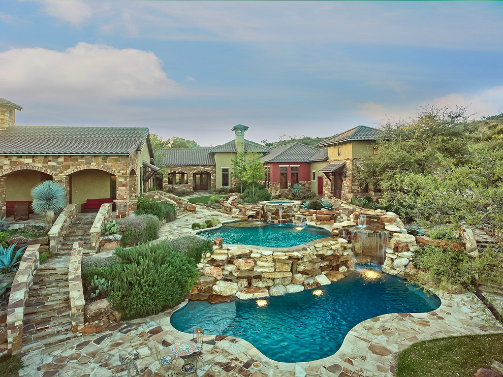 Example of a large mountain style backyard stone and custom-shaped natural hot tub design in Austin