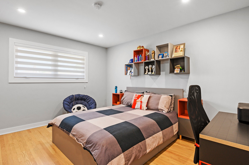 Imagen de dormitorio infantil de tamaño medio con paredes grises y suelo de madera clara