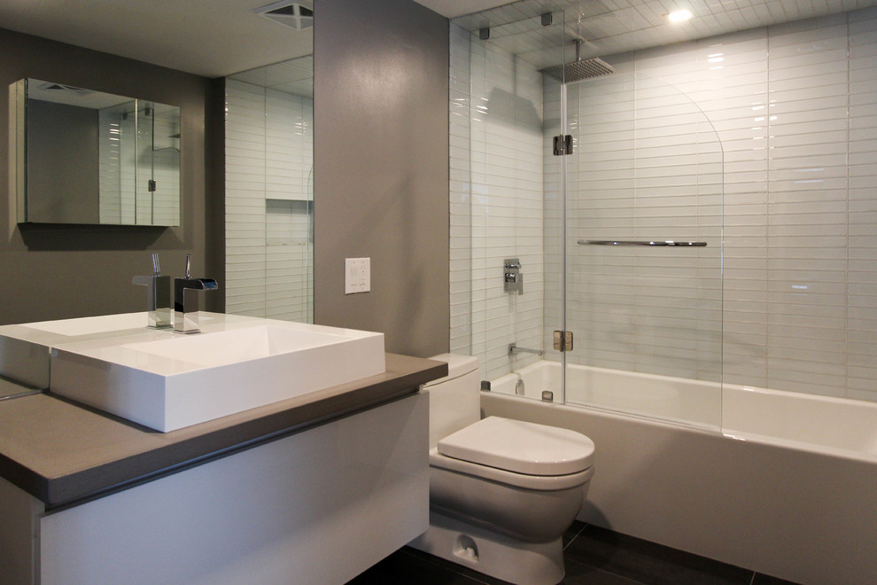 Inspiration for a small modern master bathroom in Toronto with a drop-in tub, a shower/bathtub combo, a one-piece toilet, white tile, glass tile, brown walls, slate floors, a vessel sink, engineered quartz benchtops, flat-panel cabinets and white cabinets.