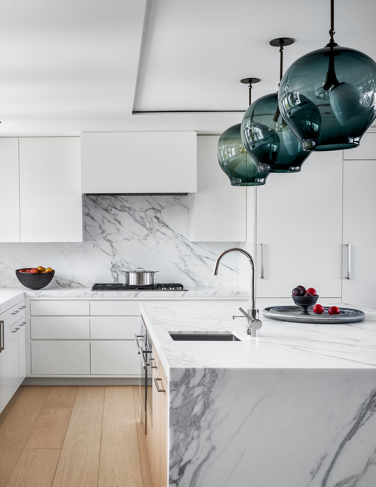 Photo of a large contemporary l-shaped eat-in kitchen in San Francisco with an undermount sink, flat-panel cabinets, white cabinets, marble benchtops, white splashback, marble splashback, panelled appliances, with island, white benchtop, light hardwood floors and beige floor.
