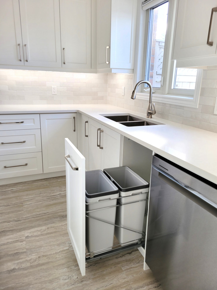 Example of a huge transitional u-shaped vinyl floor eat-in kitchen design with an undermount sink, white cabinets, quartzite countertops, gray backsplash, stone tile backsplash, stainless steel appliances, an island and white countertops