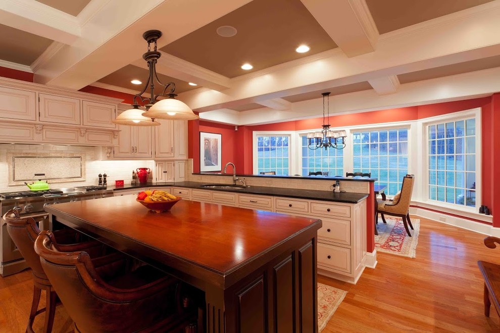 Example of a mid-sized transitional u-shaped eat-in kitchen design with raised-panel cabinets, white cabinets, soapstone countertops, beige backsplash and an island