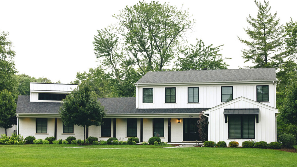 Foto della facciata di una casa bianca country a due piani con copertura mista, tetto nero e pannelli e listelle di legno