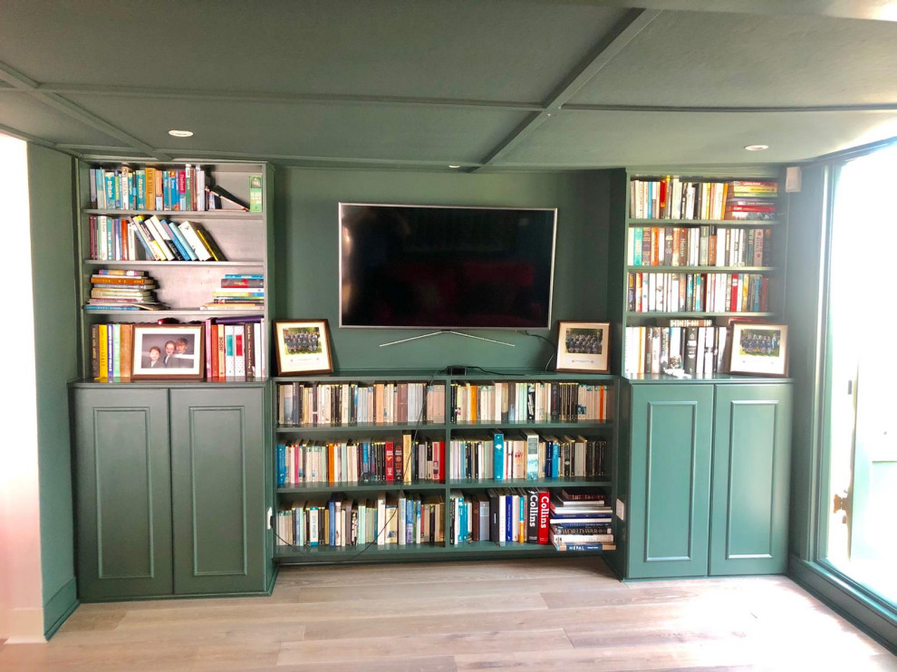 This is an example of a mid-sized enclosed home theatre in Kent with green walls, medium hardwood floors and a built-in media wall.