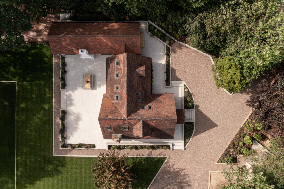 Inspiration for a large rural two floor front house exterior in Sussex with wood cladding, a pitched roof, a tiled roof, a red roof and board and batten cladding.