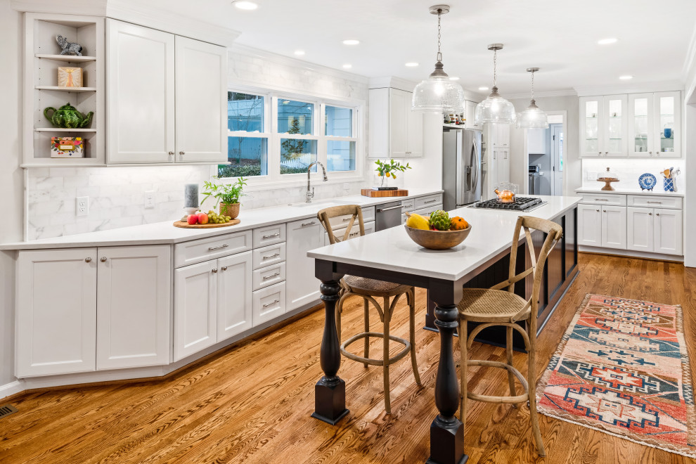 Design ideas for a mid-sized beach style l-shaped separate kitchen in Raleigh with shaker cabinets, white cabinets, quartz benchtops, white splashback, marble splashback, stainless steel appliances, medium hardwood floors, with island, brown floor, white benchtop and an undermount sink.