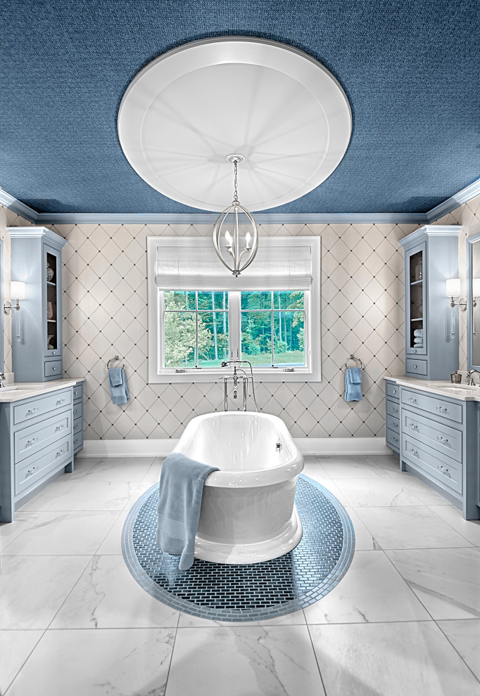 This is an example of a large country master bathroom in Grand Rapids with raised-panel cabinets, blue cabinets, a freestanding tub, multi-coloured walls, marble floors, an undermount sink, quartzite benchtops, white floor, white benchtops, a double vanity, a built-in vanity, wallpaper and wallpaper.