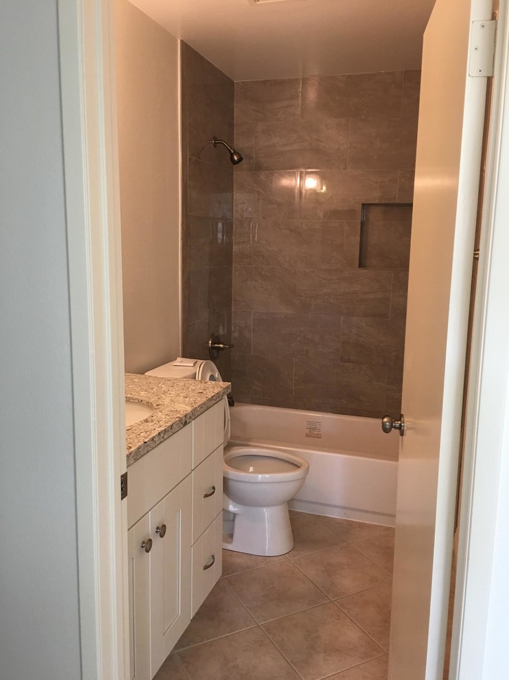 Small transitional bathroom in Orange County with shaker cabinets, white cabinets, an alcove tub, a shower/bathtub combo, a two-piece toilet, stone tile, beige walls, terra-cotta floors, an undermount sink and granite benchtops.