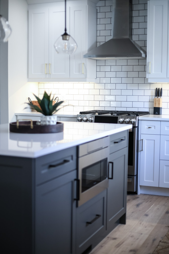 Eat-in kitchen - small l-shaped light wood floor eat-in kitchen idea with a farmhouse sink, shaker cabinets, quartz countertops, white backsplash, porcelain backsplash, stainless steel appliances, an island and white countertops