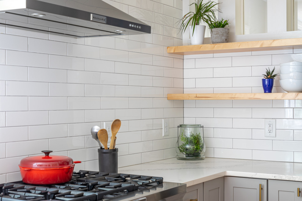 Example of a mid-sized transitional u-shaped medium tone wood floor and brown floor open concept kitchen design in Raleigh with an undermount sink, recessed-panel cabinets, blue cabinets, quartzite countertops, white backsplash, subway tile backsplash, stainless steel appliances, an island and white countertops