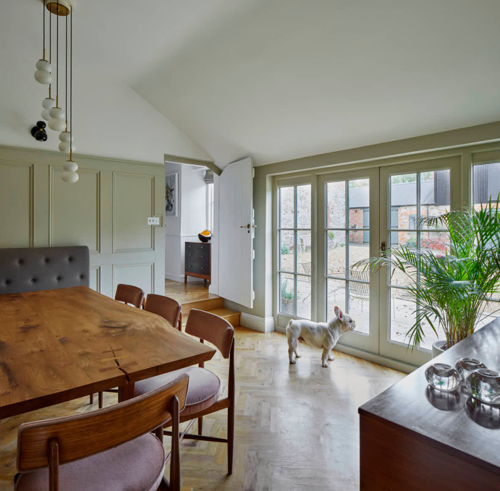 Idée de décoration pour une salle à manger champêtre fermée et de taille moyenne avec un mur vert, parquet clair, un sol marron et du lambris.