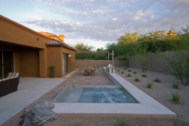 Small minimalist backyard brick and custom-shaped infinity hot tub photo in Phoenix