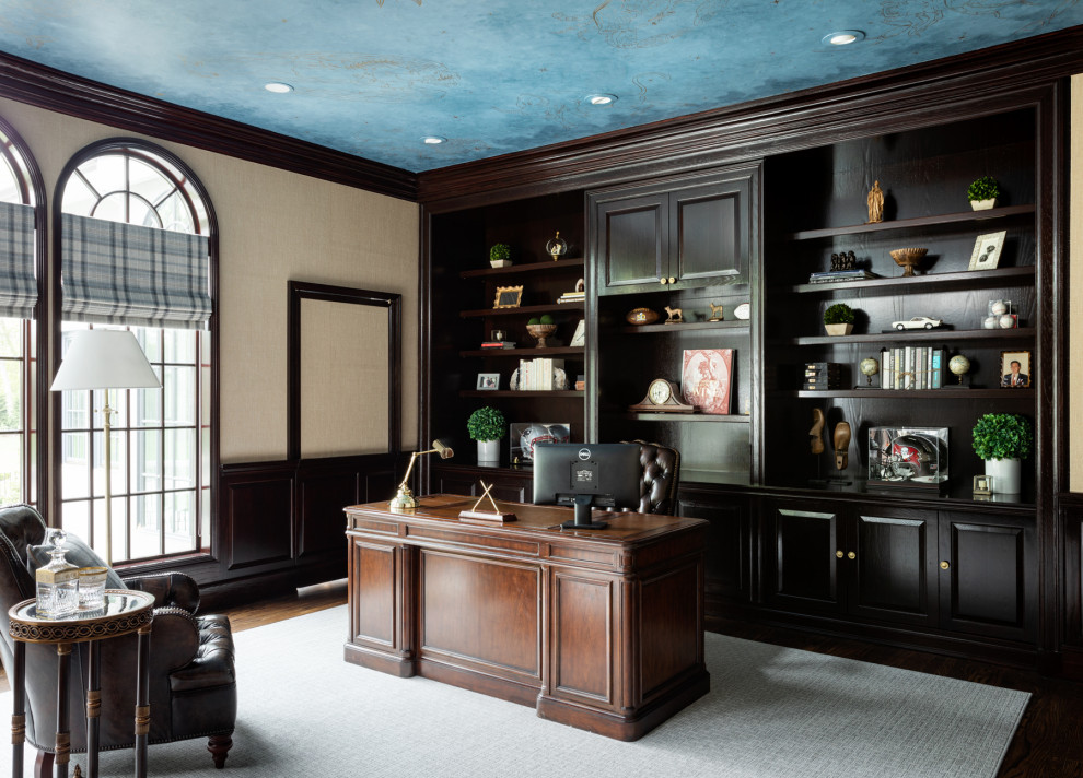 Klassisches Arbeitszimmer mit beiger Wandfarbe, braunem Holzboden, freistehendem Schreibtisch, braunem Boden, Tapetendecke, Wandpaneelen und Tapetenwänden in New York