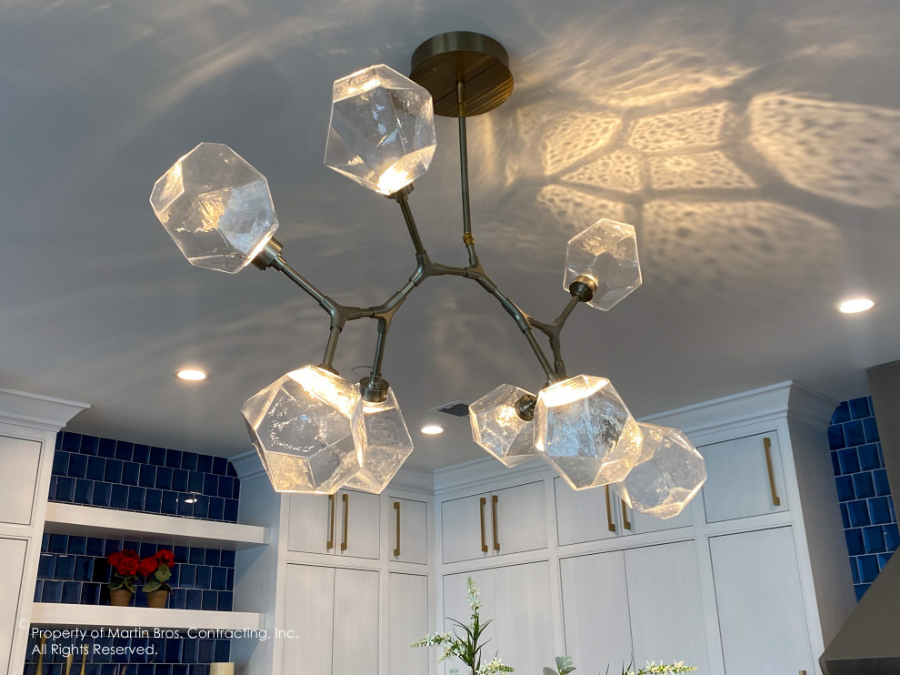 Example of a mid-sized transitional u-shaped medium tone wood floor open concept kitchen design with a single-bowl sink, flat-panel cabinets, white cabinets, blue backsplash, glass tile backsplash, stainless steel appliances, an island, quartz countertops and white countertops