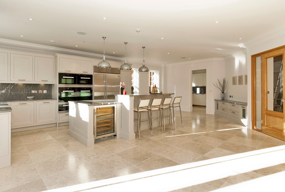Large traditional l-shaped open plan kitchen in Berkshire with a drop-in sink, shaker cabinets, grey cabinets, marble benchtops, grey splashback, marble splashback, panelled appliances and with island.