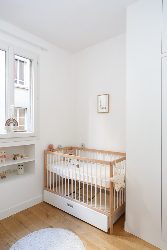 Modelo de habitación de bebé actual con paredes blancas, suelo de madera oscura y suelo marrón
