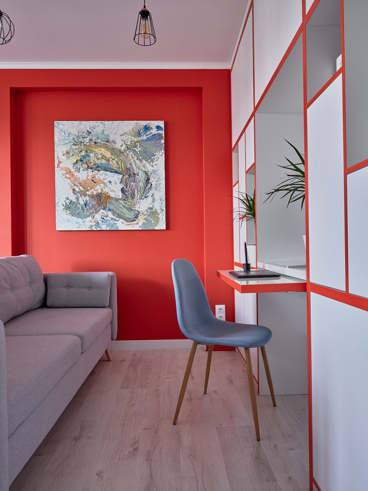 Immagine di uno studio design con pareti rosse, parquet chiaro, scrivania incassata e pavimento beige