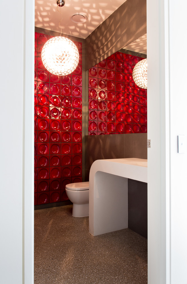 Photo of a small contemporary powder room in Melbourne with an integrated sink, red tile, concrete floors, red walls and white benchtops.