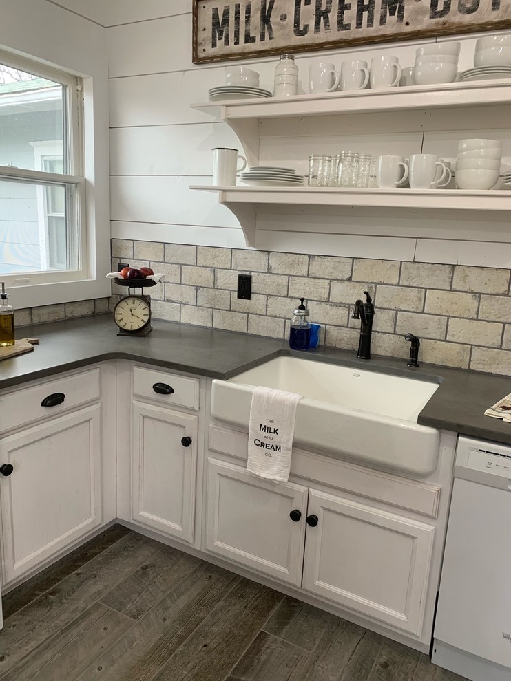 Design ideas for a mid-sized country l-shaped separate kitchen in Wichita with a farmhouse sink, raised-panel cabinets, white cabinets, quartz benchtops, grey splashback, stone tile splashback, white appliances, ceramic floors, no island, grey floor and grey benchtop.