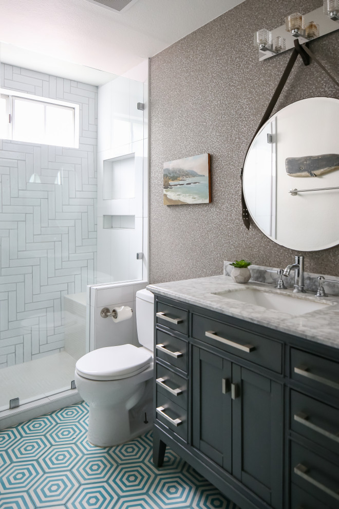 Inspiration for a beach style 3/4 bathroom in Orange County with gray tile, ceramic tile, cement tiles, marble benchtops, a hinged shower door, shaker cabinets, black cabinets, an alcove shower, a two-piece toilet, grey walls, an undermount sink and multi-coloured floor.
