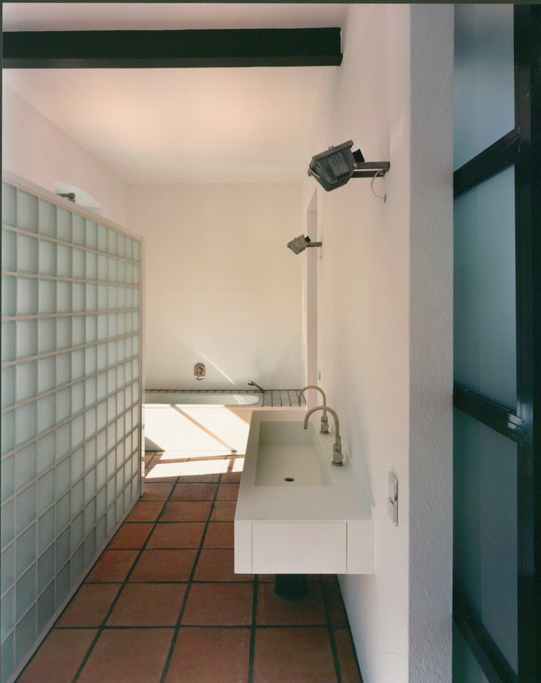 Design ideas for a contemporary 3/4 bathroom in Frankfurt with a drop-in tub, a curbless shower, terra-cotta tile, white walls and terra-cotta floors.