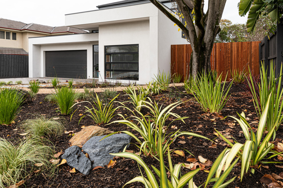 Photo of a mid-sized contemporary front yard full sun garden for spring in Melbourne with with flowerbed, decking and a wood fence.