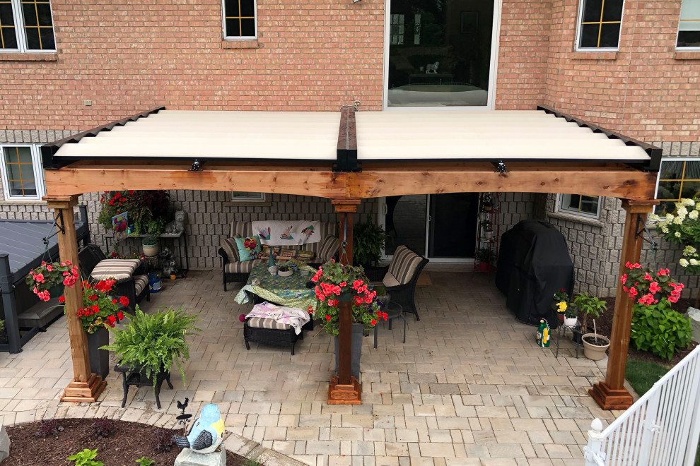Mid-sized elegant backyard stone patio photo in Toronto with a pergola