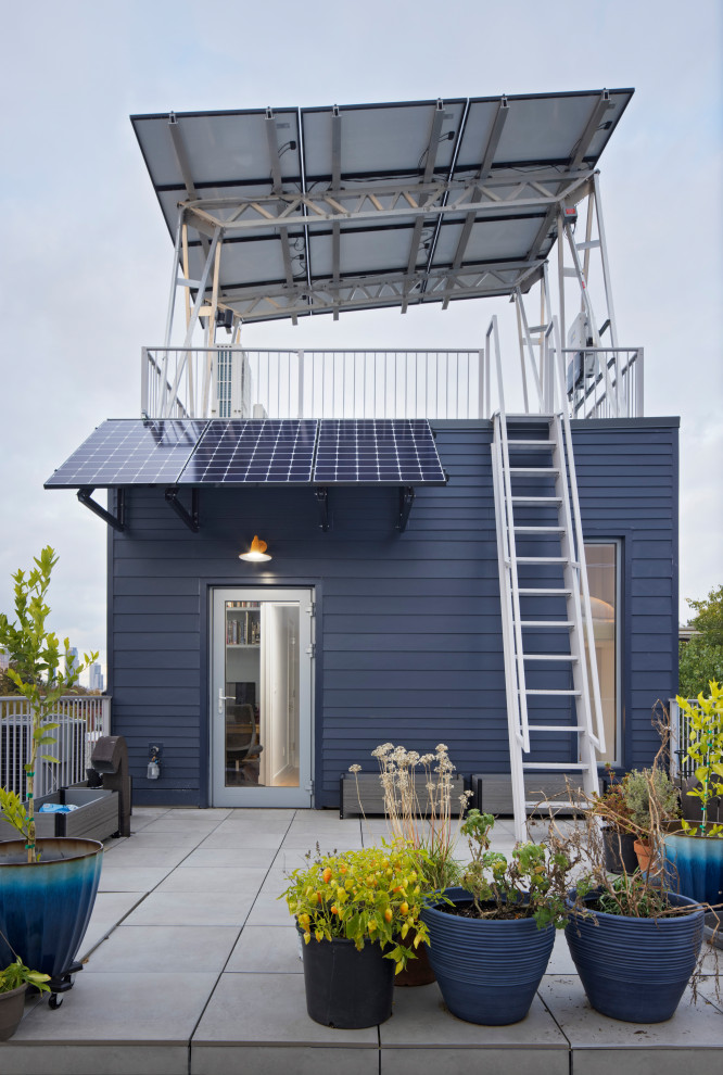 Cette photo montre une façade de maison de ville bleue tendance en panneau de béton fibré et bardage à clin de taille moyenne et à deux étages et plus avec un toit plat et un toit mixte.