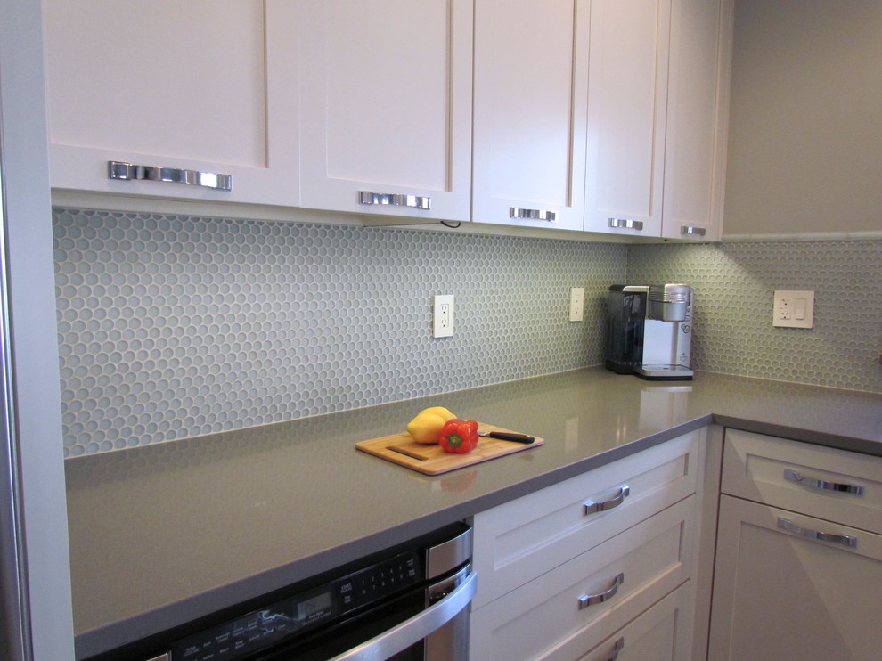 Eat-in kitchen - transitional l-shaped porcelain tile eat-in kitchen idea in Chicago with a farmhouse sink, shaker cabinets, white cabinets, quartz countertops, blue backsplash, glass tile backsplash, stainless steel appliances and an island