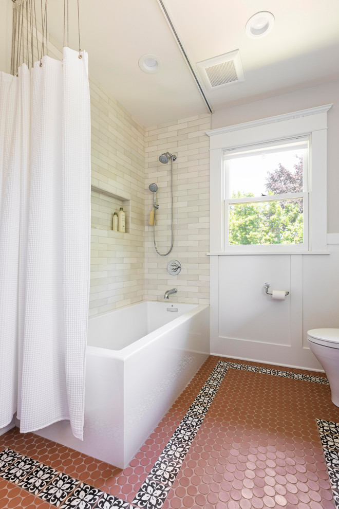 Photo of a mid-sized transitional bathroom in Portland with a corner tub, a shower/bathtub combo, a two-piece toilet, white tile, ceramic tile, grey walls, ceramic floors, orange floor, a shower curtain and decorative wall panelling.