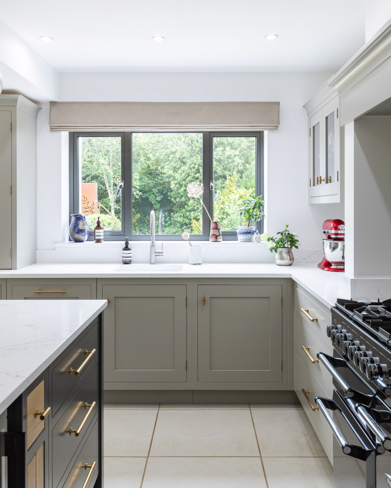 This is an example of an expansive classic l-shaped kitchen/diner in Hertfordshire with a single-bowl sink, raised-panel cabinets, grey cabinets, quartz worktops, metallic splashback, mirror splashback, limestone flooring, an island, white floors and white worktops.