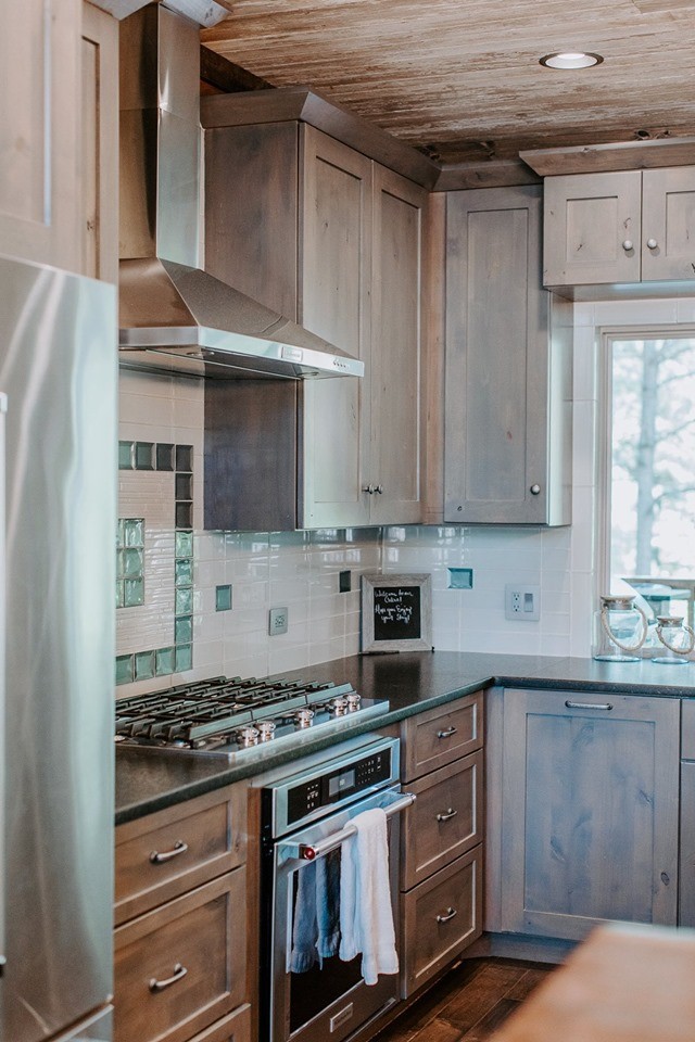 This is an example of a large country l-shaped separate kitchen in New Orleans with shaker cabinets, light wood cabinets, wood benchtops, beige splashback, stainless steel appliances and with island.