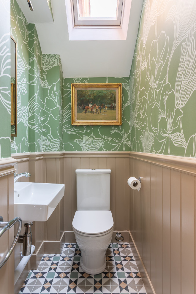 This is an example of a small traditional cloakroom in Kent with a one-piece toilet, beige walls, porcelain flooring, a wall-mounted sink, brown floors, a dado rail and wallpapered walls.