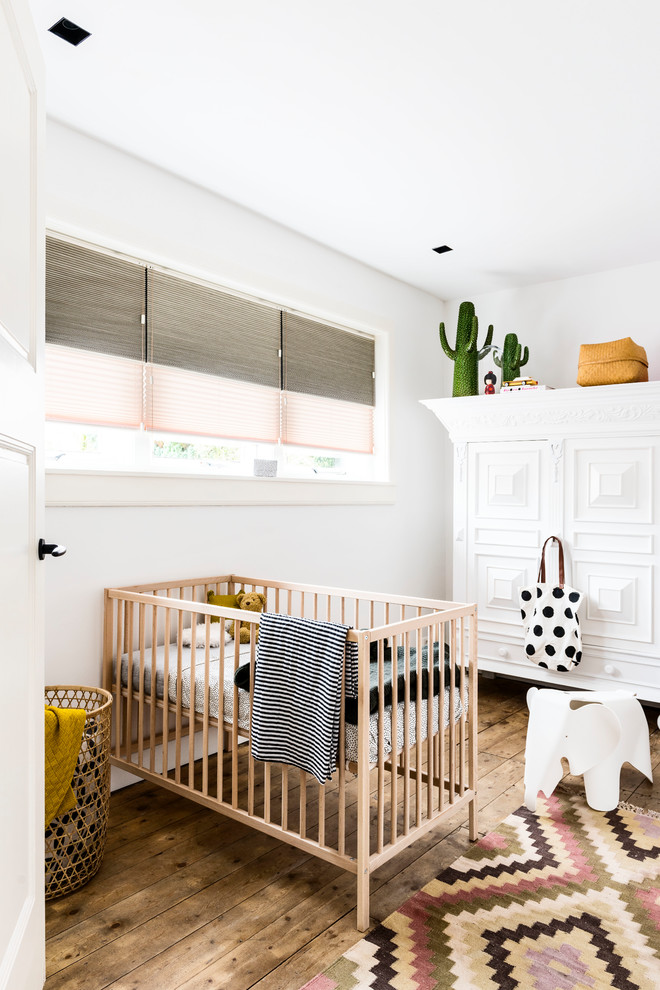 This is an example of a mid-sized scandinavian nursery for girls in Other with white walls, medium hardwood floors and brown floor.