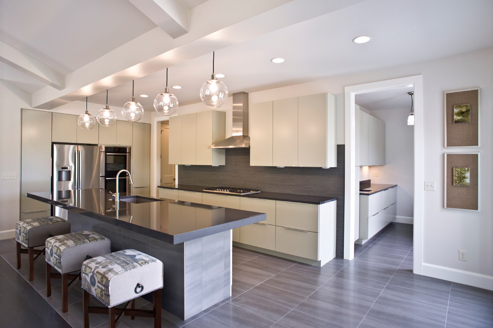 Inspiration for a modern kitchen remodel with an undermount sink, flat-panel cabinets, gray cabinets, stainless steel appliances, gray backsplash, white walls and an island