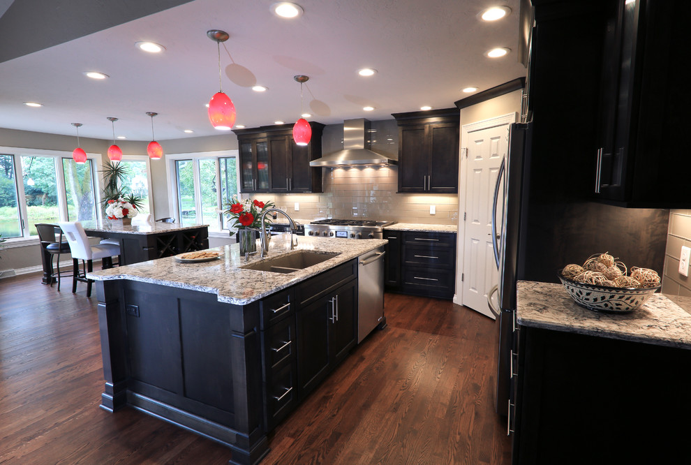 Kitchen - transitional dark wood floor kitchen idea in Milwaukee with an undermount sink, shaker cabinets, quartz countertops, glass tile backsplash, stainless steel appliances and two islands