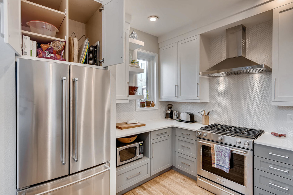 Example of a small transitional u-shaped light wood floor and brown floor eat-in kitchen design in Denver with an undermount sink, shaker cabinets, white cabinets, granite countertops, white backsplash, ceramic backsplash, stainless steel appliances, a peninsula and white countertops
