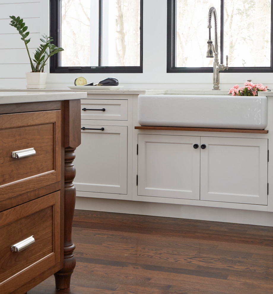 Photo of a large country u-shaped open plan kitchen in Chicago with a farmhouse sink, recessed-panel cabinets, white cabinets, quartz benchtops, white splashback, shiplap splashback, stainless steel appliances, medium hardwood floors, with island, brown floor and white benchtop.