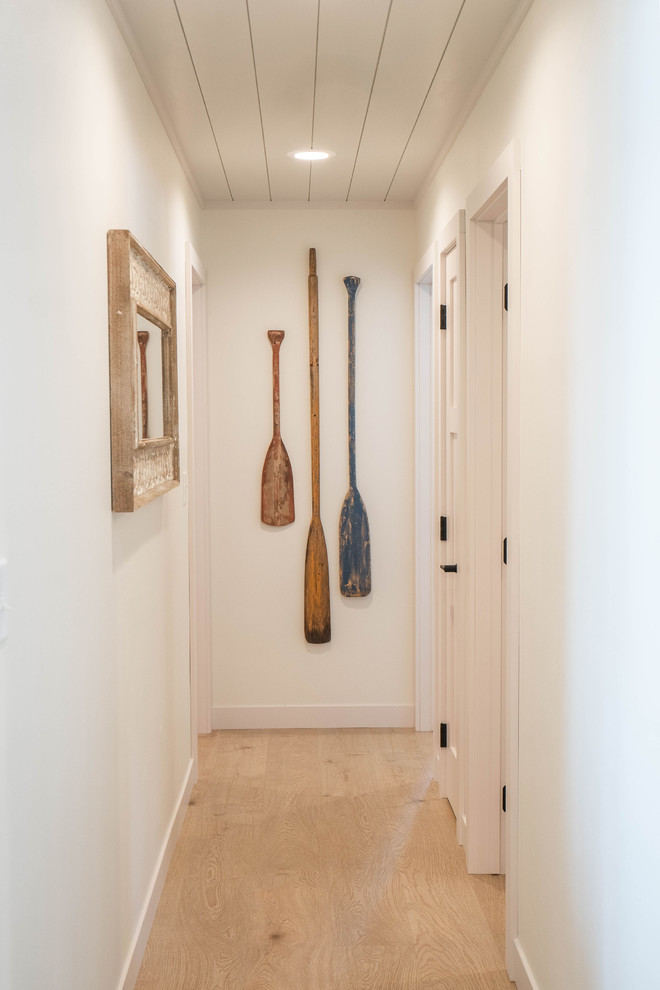Design ideas for a mid-sized beach style hallway in Other with white walls, light hardwood floors and beige floor.