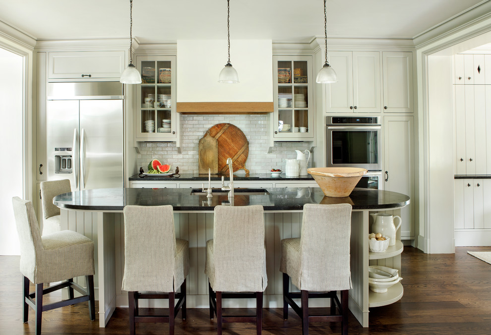 Inspiration for a traditional galley separate kitchen in Atlanta with an undermount sink, recessed-panel cabinets, beige cabinets, white splashback, subway tile splashback, stainless steel appliances, dark hardwood floors, with island and brown floor.