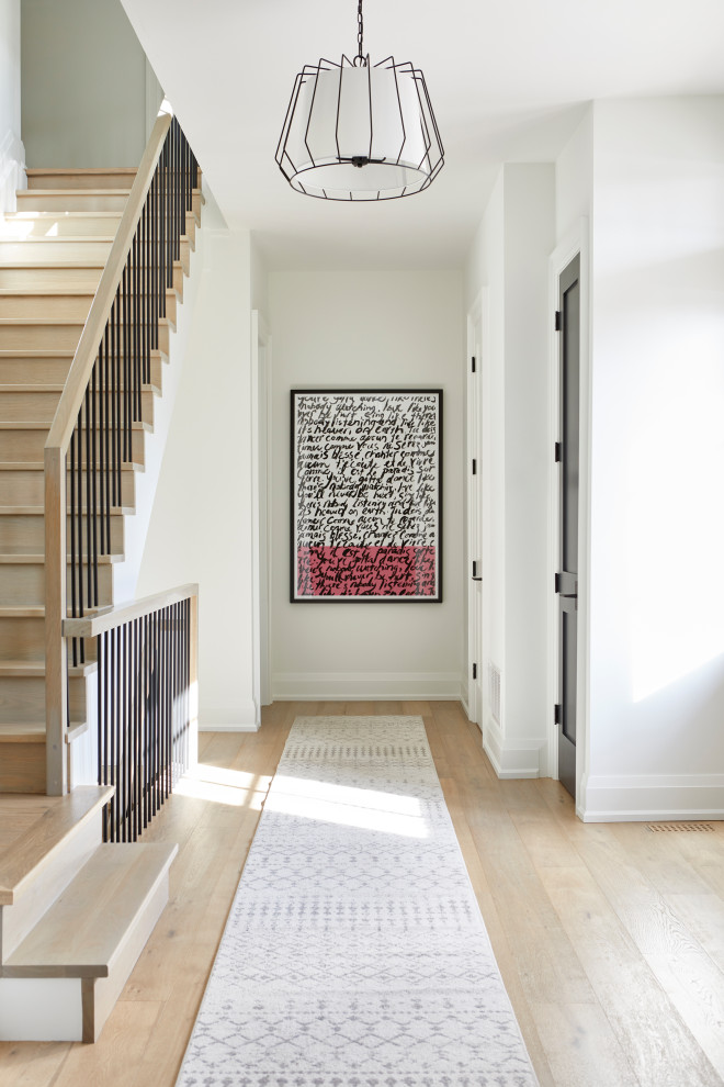 トロントにある高級な中くらいなトランジショナルスタイルのおしゃれな玄関ロビー (白い壁、淡色無垢フローリング、濃色木目調のドア、ベージュの床) の写真