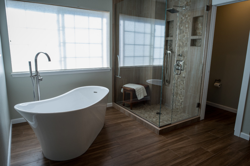 Inspiration for a large transitional master bathroom in Denver with furniture-like cabinets, brown cabinets, a freestanding tub, a corner shower, a one-piece toilet, beige tile, pebble tile, green walls, porcelain floors, an undermount sink and engineered quartz benchtops.