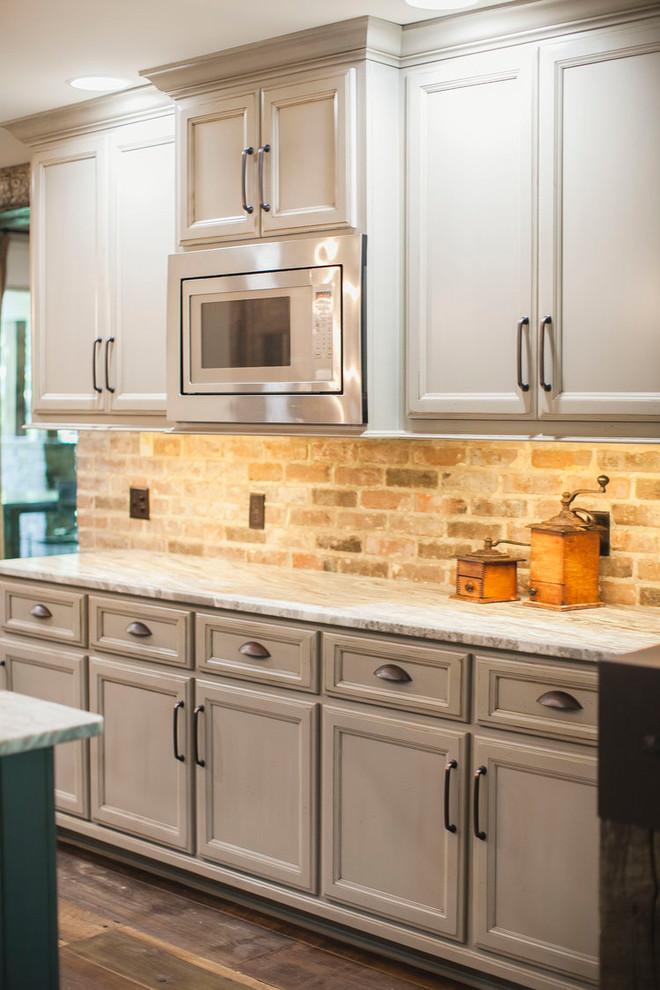 Inspiration for a rustic u-shaped dark wood floor and brown floor eat-in kitchen remodel with a farmhouse sink, raised-panel cabinets, white cabinets, marble countertops, red backsplash, brick backsplash, colored appliances, an island and gray countertops