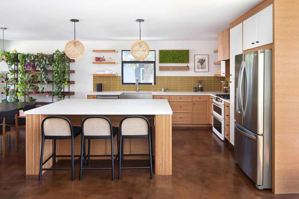 Design ideas for a large midcentury l-shaped open plan kitchen in Los Angeles with a farmhouse sink, beaded inset cabinets, light wood cabinets, quartz benchtops, green splashback, porcelain splashback, stainless steel appliances, concrete floors, with island, brown floor and white benchtop.