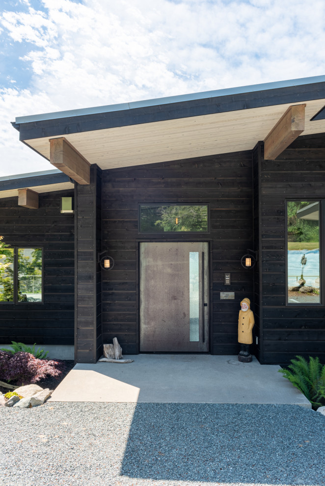 Cette image montre une façade de maison noire minimaliste en bois et bardage à clin de taille moyenne et à un étage avec un toit en appentis, un toit en métal et un toit gris.