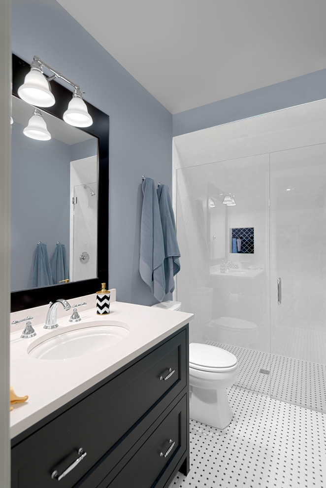 This is an example of a mid-sized transitional 3/4 bathroom in Grand Rapids with shaker cabinets, black cabinets, a curbless shower, a two-piece toilet, white tile, ceramic tile, blue walls, mosaic tile floors, an undermount sink, engineered quartz benchtops, multi-coloured floor, a hinged shower door, white benchtops, a single vanity and a built-in vanity.