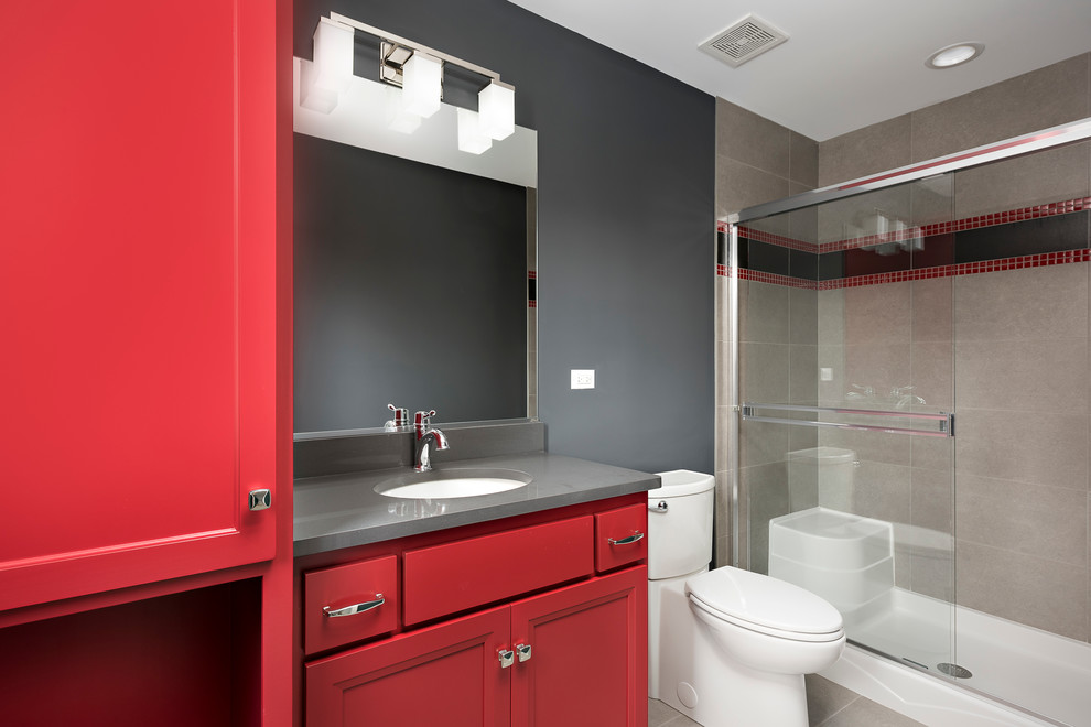 Photo of a small transitional kids bathroom in Chicago with red cabinets, a sliding shower screen, recessed-panel cabinets, an alcove shower, a two-piece toilet, ceramic tile, grey walls, ceramic floors, an undermount sink and beige floor.