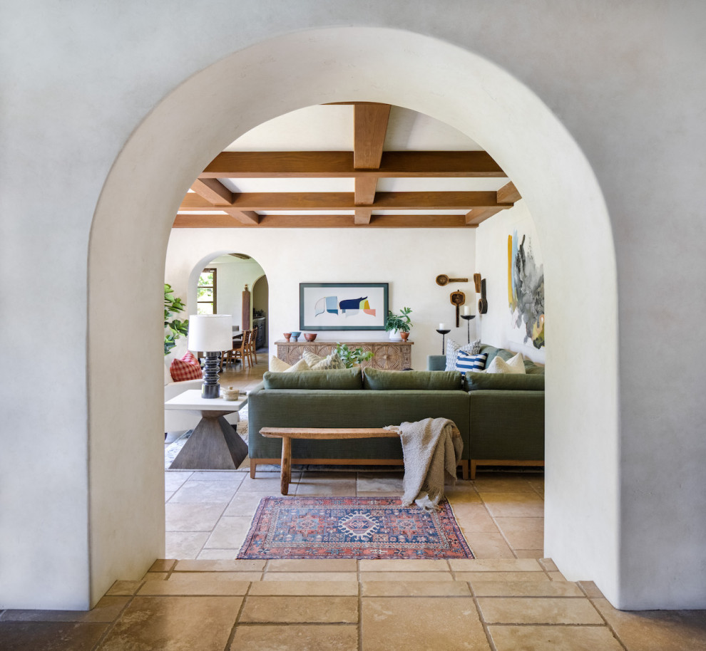 Inspiration for a mid-sized mediterranean open concept family room in Orange County with white walls, travertine floors, no fireplace and beige floor.