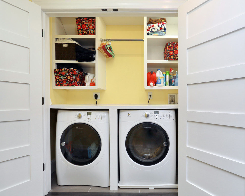 Inspiration for a small modern single-wall laundry cupboard in Boston with open cabinets, yellow walls, light hardwood floors, a side-by-side washer and dryer and white cabinets.